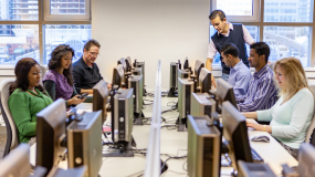 Groupe de personnes en session de formation devant écrans d'ordinateurs