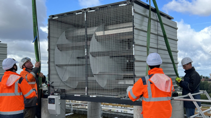 Quatre personnes installent une box éolienne sur le toit d'un immeuble